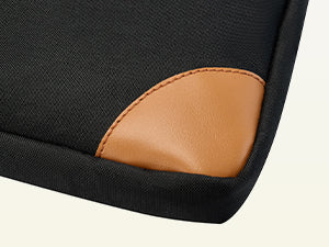 Close-up of a black bag with a brown leather patch on a light beige background